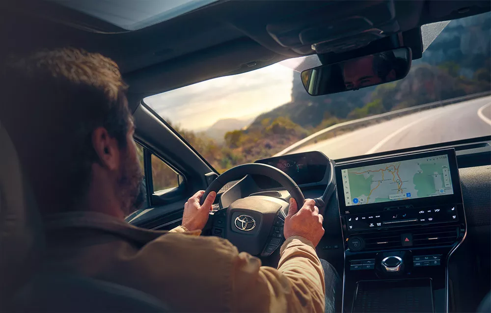 Mann sitzt im Toyota und blickt auf kurvige Straße
